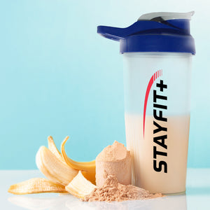 Protein shaker bottle next to a pile of powder and fruit