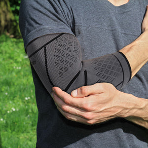 Athlete wearing an elbow compression sleeve holding his elbow